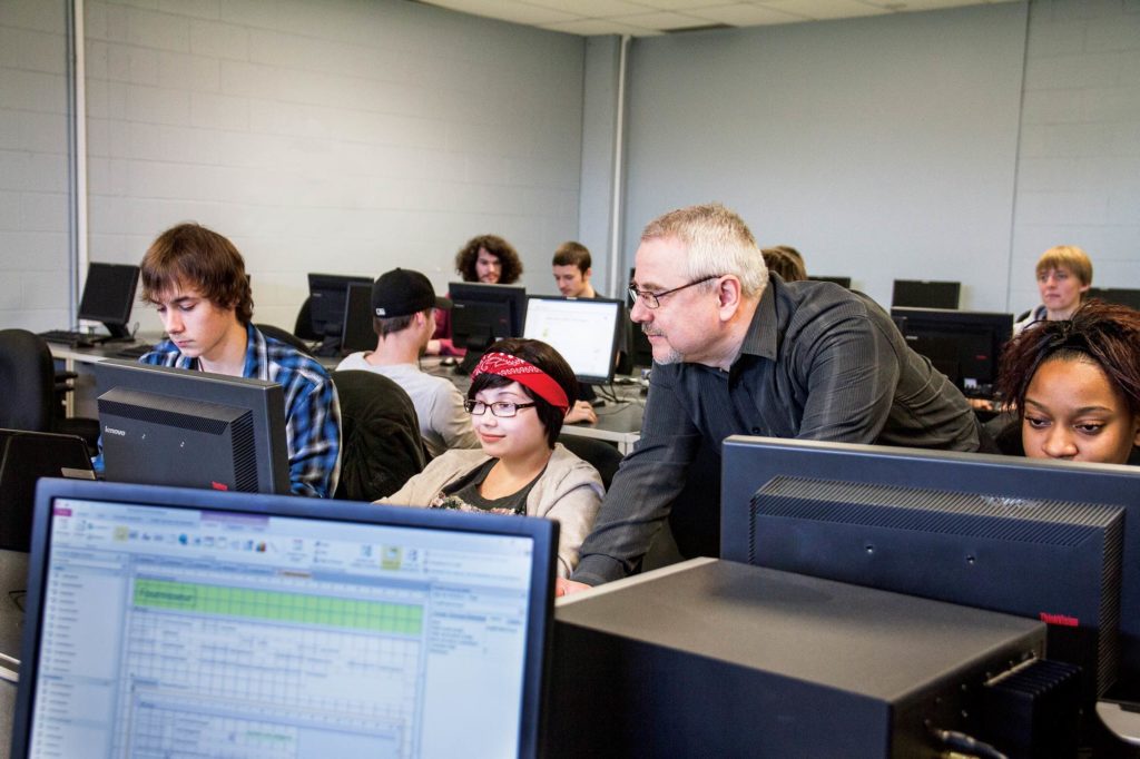 Enseignant avec des étudiants dans un local informatique