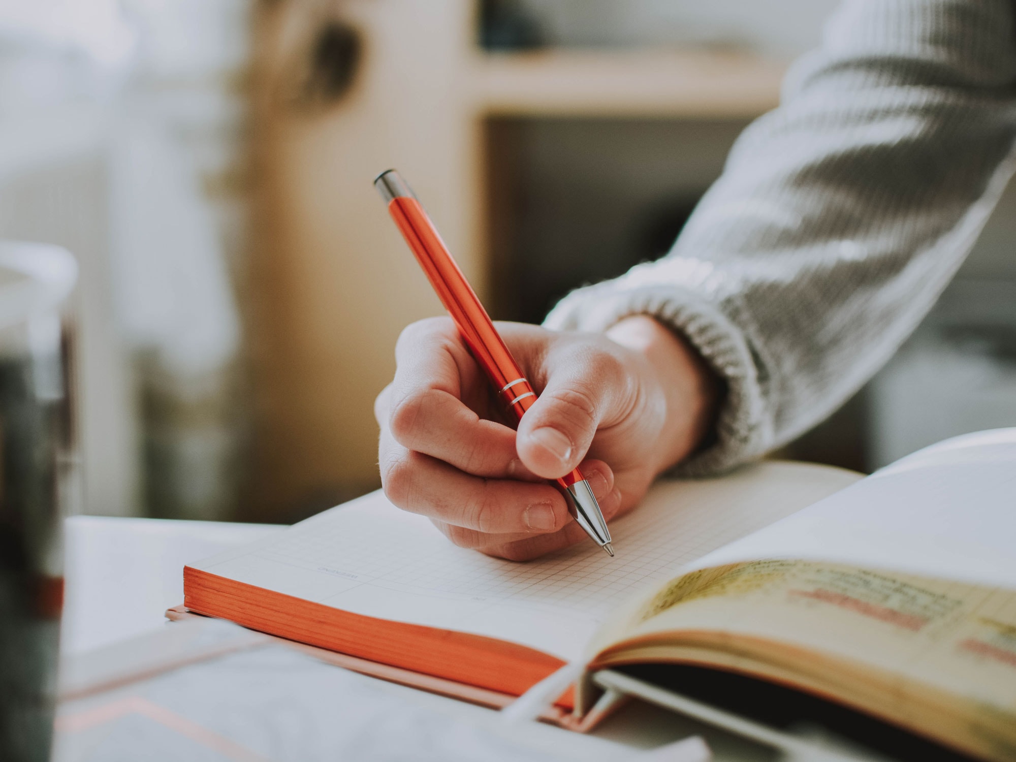 person-holding-orange-pen-1925536